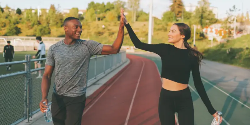 black man and woman at track running high five on way to their body composition test at BodymetRx Kansas City